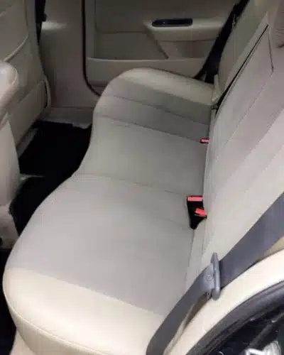Banquette arrière d'une voiture avec sièges en tissu gris clair et boucles de ceintures de sécurité.