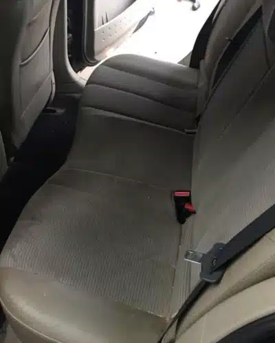 Banquette arrière grise de voiture avec des taches d'usure sur le tissu avant nettoyage professionnel.