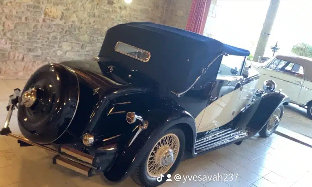 Automobile de collection bicolore avec capote bleue exposée dans un garage en pierre. @yvesavah237